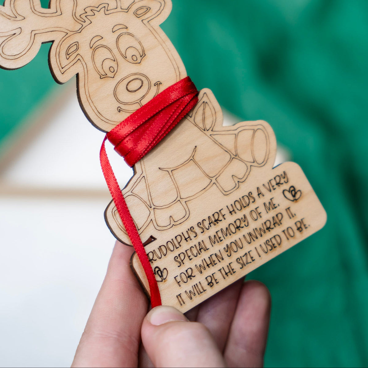 Close up of the text on the reindeer ornament that reads 'rudolph's scarf holds a very special memory of me. For when you unwrap it, it will be the size I used to be.