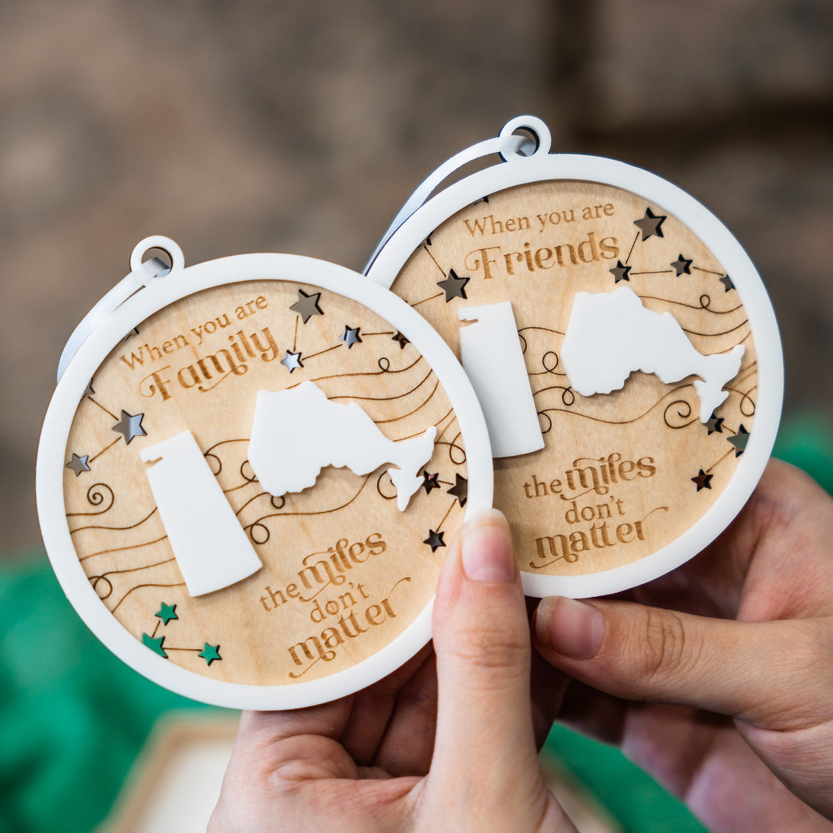 Two round wooden keepsake medallions held in hands against a blurred background. One medallion is engraved with 'When you are Family' and the other with 'When you are Friends', both featuring a white silhouette of Kentucky, stars, and the phrase 'the wilfs don't matter'.