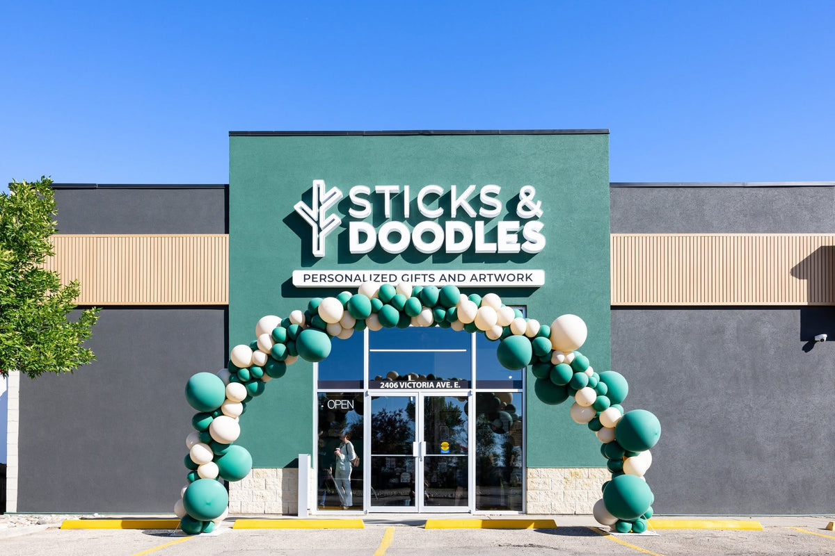 Sticks & Doodles green storefront, brand sign and balloon arch at 2406 Victoria Ave E